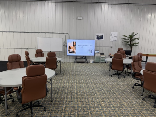 Sharalife training classroom with round tables, rolling chairs, and presentation screen