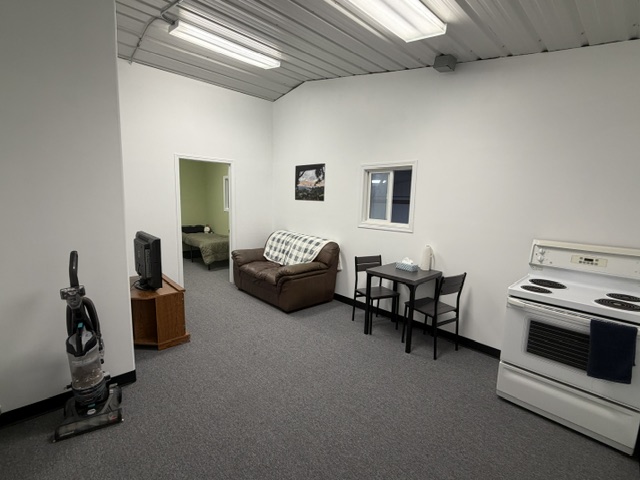 Sharalife staff lounge with sofa, dining table, kitchenette appliances, and television